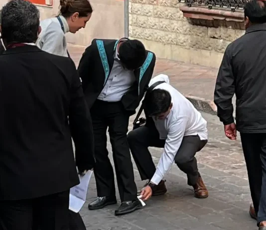 Funcionarios se agachan para limpiarle los zapatos a Hugo Aguilar